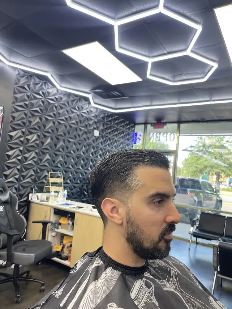 A slicked-back cut and full beard, side view