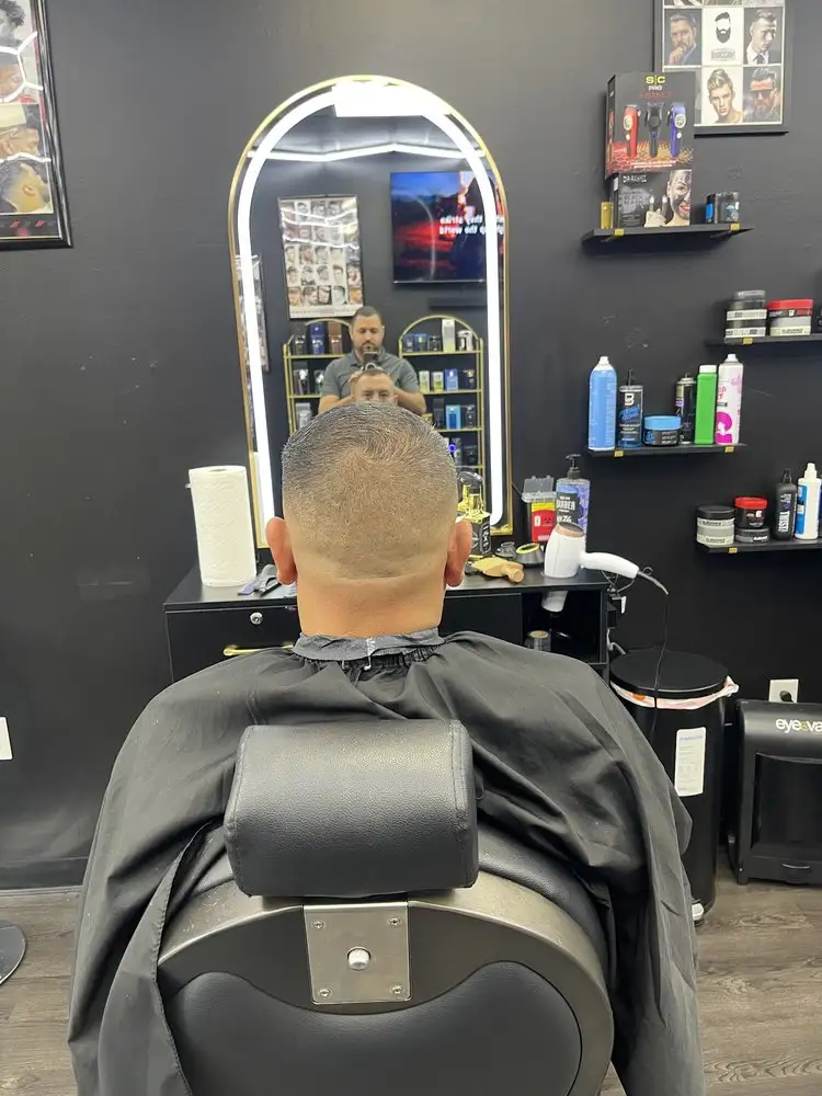 A client mid-cut, seen from behind, facing a lit mirror